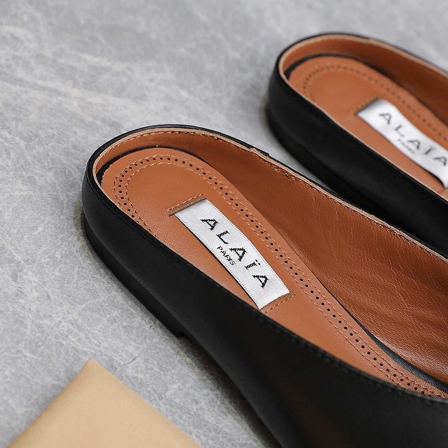 ALAIA FLAT MULE IN BLACK LAMBSKIN